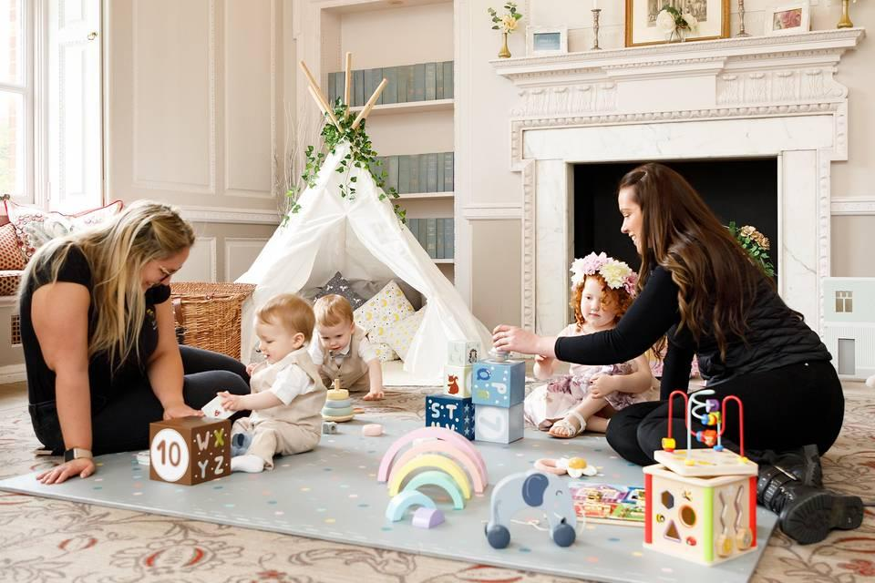 Nannies engaging infants and toddlers with sensory play indoors